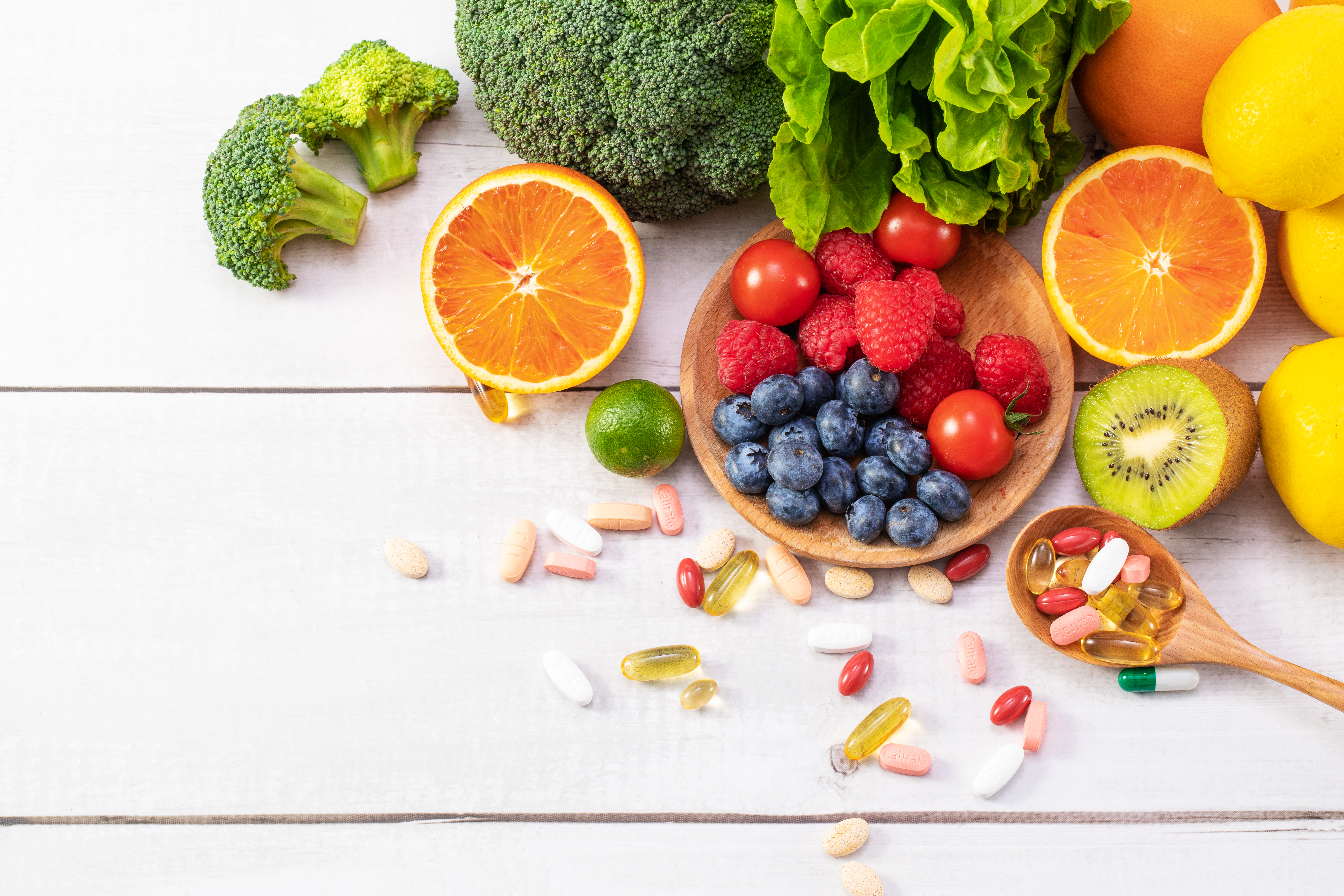 top view of fresh fruits and vegetables with different medicine on a wooden spoon